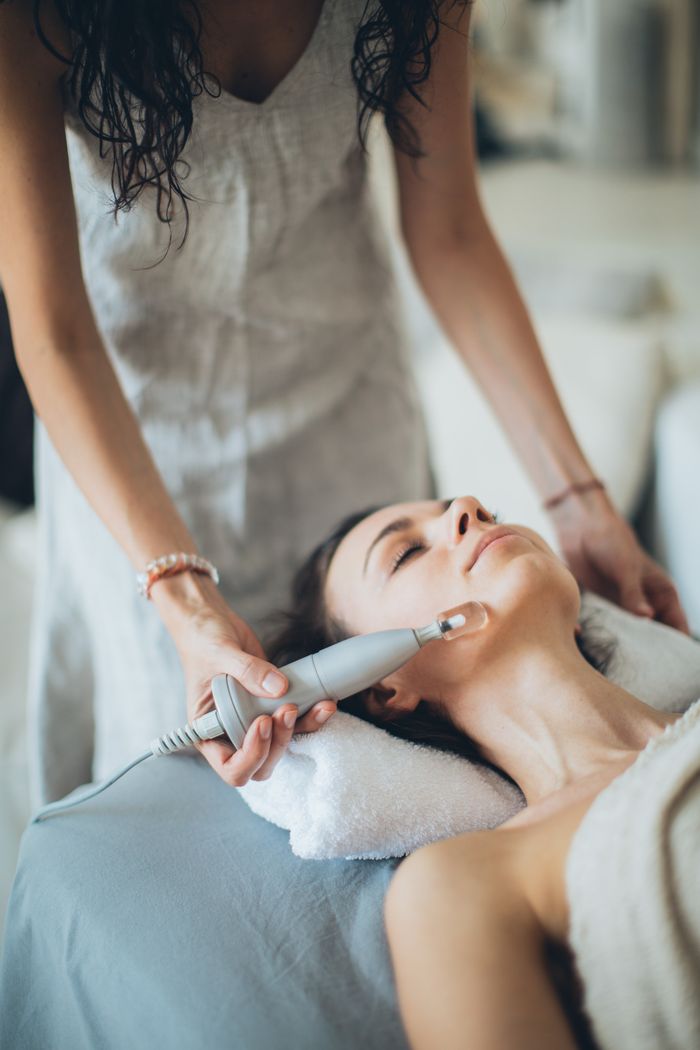 services-04 A woman enjoying a relaxing facial treatment using advanced technology at a spa. Perfect for wellness promotion.
